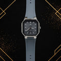 Elegance luxury men's quartz watch featuring a dark grey horizontal textured dial, polished silver octagonal case, and slate grey silicone strap, shown in a straight-on front view against a black and gold abstract background.