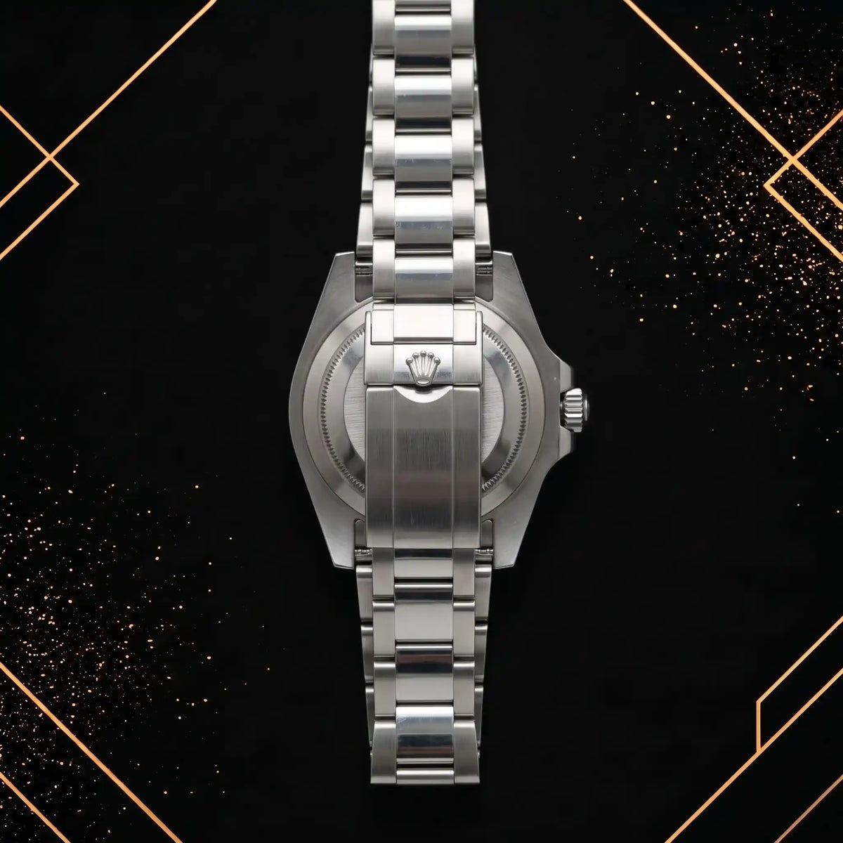 Back view of a stainless steel sports watch showing the brushed solid caseback, crown logo engraved folding clasp, and link structure.