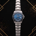 Rolex Submariner stainless steel watch featuring a blue dial, blue rotating bezel, silver bracelet, and date display – front view