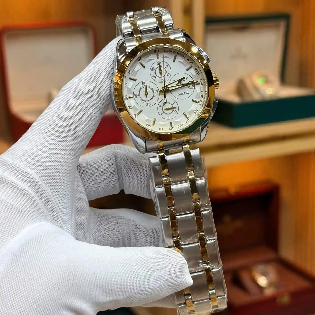 Tissot Chronograph Two-Tone Gold and Silver Men's Watch with White Dial, Three Sub-dials, and Stainless Steel Strap, held by a gloved hand